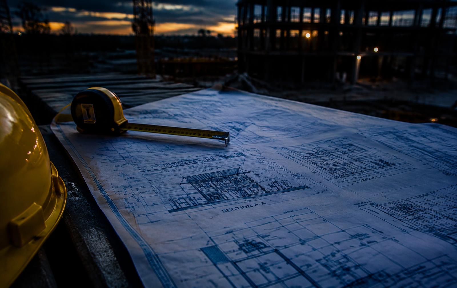 Construction blueprints on a jobsite table at dusk